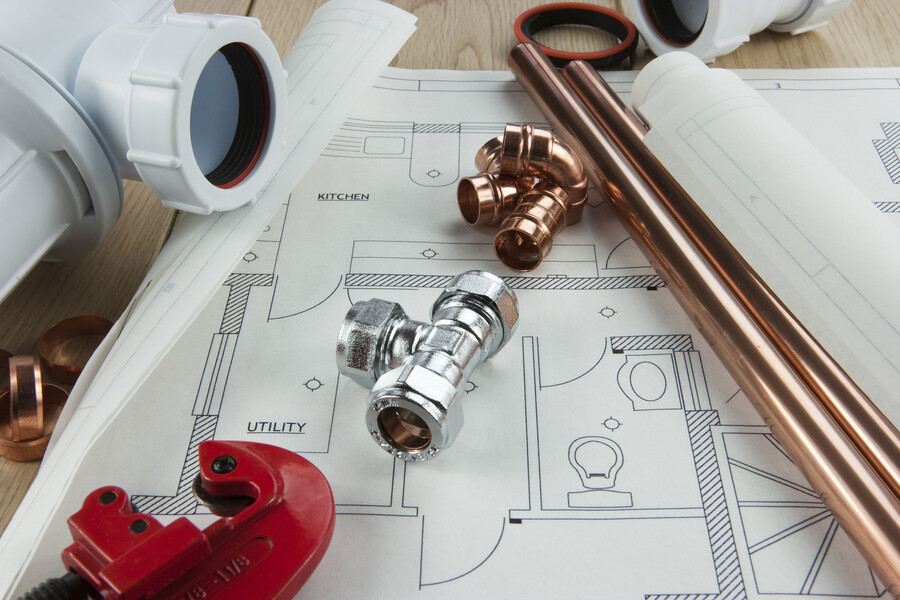 Copper pipes and plumbing fittings on a house blueprint for kitchen and utility room planning