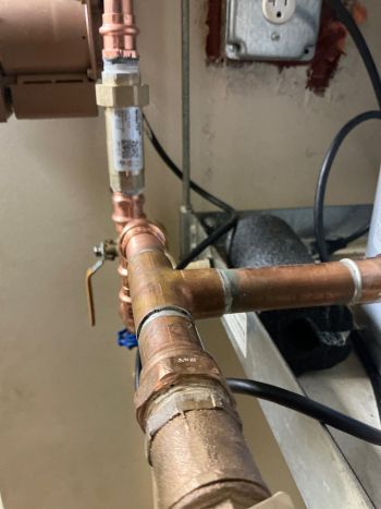 Copper plumbing pipes and valve in a utility room beside a water heater